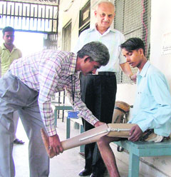 Pradeep Kumar fixes a prosthetics foot on a man.
