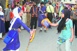 Sikh girls play gatka at a nagar kirtan in Dehradun on Monday to mark the tercentenary celebrations of Guru Granth Sahib.