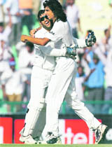 Mahendra Singh Dhoni and Ishant Sharma (R) celebrate the dismissal of Australias Shane Watson on the fourth day of the second Test in Mohali on Monday. 