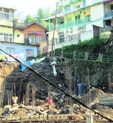 An electric pole hangs precariously after a road caved in due to digging for new construction in Kaithu