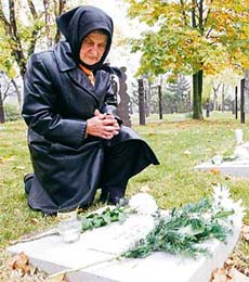 A woman prays over the grave of her relative, who was killed during Hungary's 1956 anti-communist revolution, in Budapest's central cemetery