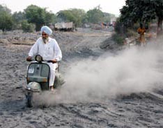 Dust is raised as a scooterist drives through a heap of fly ash in Bathinda on Friday. Fly ash has become a major threat to peoples health here.