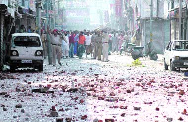 Shattered glass, bricks and stones strewn on the road near Ali Mohalla in Jalandhar on Friday. Tribune photo: Pawan Sharma