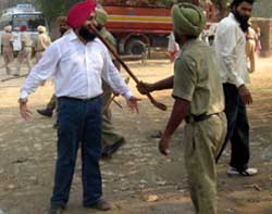 A computer teacher challenges a policeman to beat him up at Kheowali village in Muktsar on Sunday.
