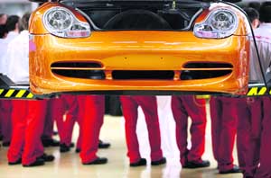 Apprentices of German sports car maker Porsche stand behind a Porsche car at the Porsche Leipzig GmbH plant in Leipzig, eastern Germany, on Monday. Porsche said on Monday it now controls 74.1 per cent in Volkswagen, Europe's biggest automaker, via a 42.6 percent direct equity stake and options giving it another 31.5 per cent. 