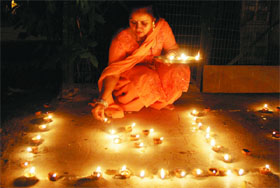 A lady decorates diyas outside her home.