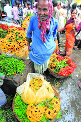 A farmer waits for customers at a wholesale flower market in Kolkata on Monday. Many villagers travel 50 miles to sell flowers.