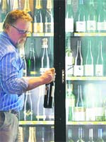 A customer selects a wine bottle at a liquor store in Sydney. Fosters Group, the worlds second-largest wine group, has delayed a decision on the fate of its troubled wine business until early 2009 while it examines opportunities, it said on Wednesday