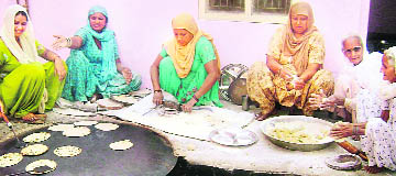 Women prepare ‘langar’ at community kitchen at the Vishawkarma temple at Ahmedgarh on Wednesday.