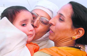 A Kashmiri woman pilgrim hugs a child and another relative before leaving for Haj at Haj House in Srinagar on Thursday