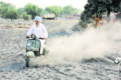 A scooterist drives through an open place where fly ash has been dumped