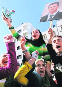 Syrian students shout slogans against the US as they wave a poster of President Bashar al-Assad during a demonstration in Damascus