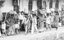 Migrants bound for Bihar carry their luggage at the Ambala railway station for Chhatt Pooja on Friday.