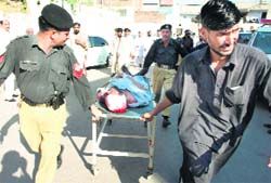 Pakistani policemen push a stretcher carrying an injured colleague upon arrival at a hospital in Peshawar on Friday after the suicide attack in the town of Mardan.