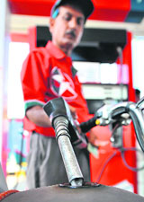 A Pakistani employee of a private gasoline station fills the tank of a motorcycle in Karachi on Saturday.