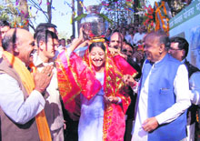 A woman carries a pitcher on her head after the inauguration of the Bhota drinking water scheme as Chief Minister Prem Kumar Dhumal looks on.