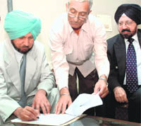 Justice Baldev Singh (left) signs joining papers at the Punjab State Human Rights Commission in the presence of chairman Justice R.S. Mongia in Chandigarh on Tuesday.