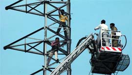 Police and Fire Service personnel request Amit and Sanjay to come down from a tower. They had climbed the tower to press for their demands at Rohini in New Delhi on Wednesday. 