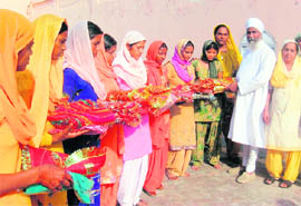 Baba Jaspal Singh and others give shagun to the brides in batches.
