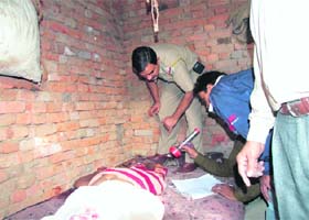 Police officials examine the body of a man who was found murdered in Palam Vihar, Gurgaon