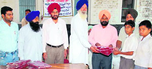 SBoP manager Bharpoor Singh presents woollen garments to a student at Nathumajra, near Ahmedgarh, on Thursday.