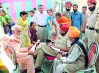 Policeman Shish Singh writes applications for uneducated complainants at a sangat darshan in Ludhiana on Friday.