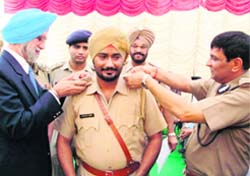 DGP N.P.S. Aulakh (left) and IGP (border range) R.P. Mittal fix stars on the shoulders of ASI Gurpreet Singh at Zira on Saturday. The ASI had nabbed terrorists and recovered a huge cache of arms