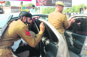 Policemen remove tinted films from vehicles in Jammu on Sunday as a precautionary security measure.