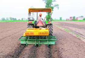 A farmer demonstrates a bed-making-cum-direct-paddy seed drilling equipment at a village in Amritsar