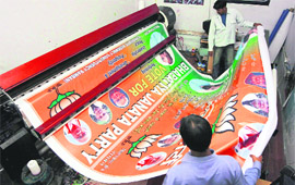 People associated with odd jobs having a good time by preparing campaign items for the upcoming assembly elections.