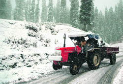 A tractor moves towards Tangmarg after the seasons first and heavy snowfall at Gulmarg in Kashmir on Thursday.
