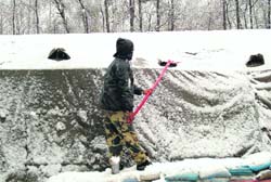 A CRPF jawan clears snow in Anantnag district on Saturday.