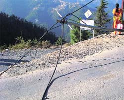Telephone wires lie on the road hanging from a tilted pole at Bharari, Shimla. 