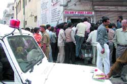 People and Delhi police personnel gather outside the Samaypur Badli branch of State Bank of Bikaner and Jaipur that was robbed on Monday. 