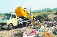 A Municipal Corporation vehicle dumps solid waste in the Tawi riverbed.
