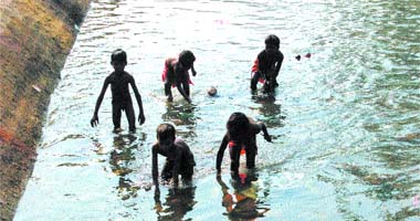 Kids search for coins thrown into a canal as religious offerings by passers-by in Jalandhar