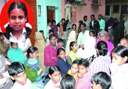 People gather outside the residence of Sonia who was mowed down by a Blueline bus near Deoli village in South Delhi