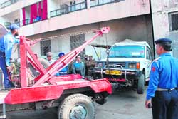 Traffic police personnel toe away vehicles parked in a no-parking area in Jammu. 