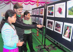 Wildlife photographer Bhumesh Bharti interacts with a visitor at the photo exhibition in Dehradun on Thursday. 