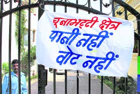 A poster tied to the gate of a house says No water, no vote, a boycott message forthcoming state Assembly elections, in Bhopal