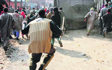 A policeman chases away a group of anti-poll protesters during the second phase of elections in Barsoo, 30 km from Srinagar, on Sunday.