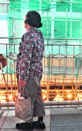 A woman stands on an elevated walkway in front of a building under renovation in Hong Kong