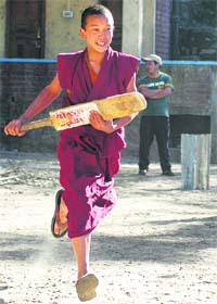 A Tibetan Buddhist monk plays cricket outside a monastery in Shimla