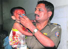 A policeman gives water to an injured child at a hospital.