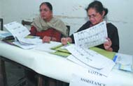 Election officers check voter lists at Irwin School in New Delhi