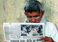 A man goes through a newspaper after terrorists strike in Mumbai, at Connaught Place