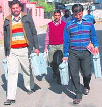 Officers carry electronic voting machines for th onging Assembly elections in Jammu.