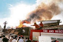 Pakistani firefighters attempt to extinguish fires after rioters set ablaze several shops at a market in Karachi on Sunday.