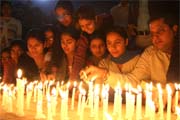 People lighting candles at the railway station on Monday evening.