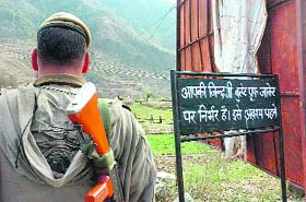 A soldier stands guard near a board in a security forces camp in Than Mandi (Rajouri district), reminding them of the importance of bullet-proof jackets in the militancy-infested state